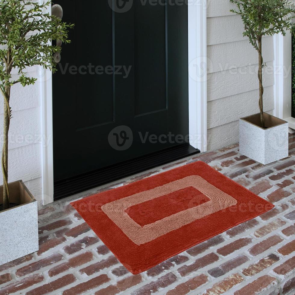 Designer Welcome Entry Doormat Placed on Solid Brick Floor Outside Entry Door with Plants photo