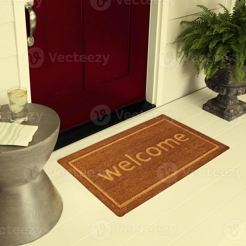 felpudo de entrada de bienvenida de diseñador colocado en el suelo fuera de la puerta de entrada con plantas y bebida de hielo de limón foto