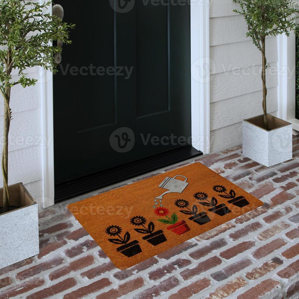 Designer Welcome Entry Doormat Placed on Solid Brick Floor Outside Entry Door with Plants photo