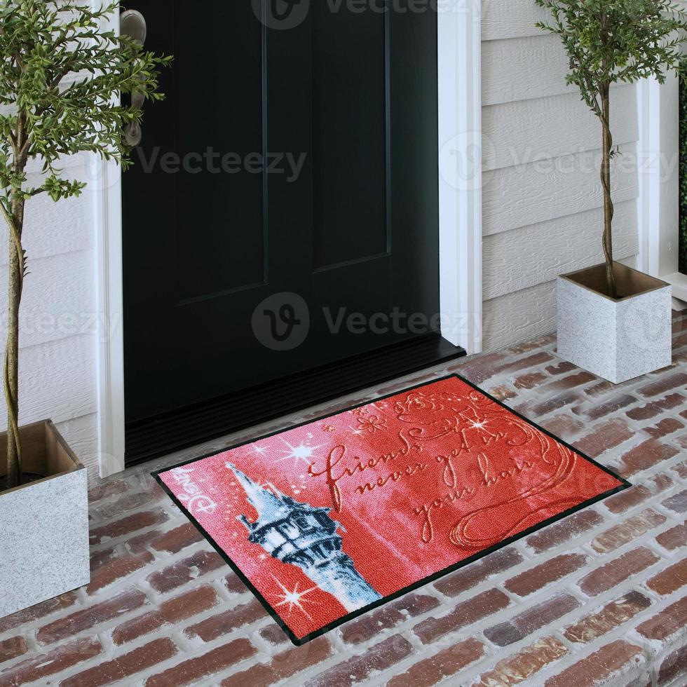 Designer Welcome Entry Doormat Placed on Solid Brick Floor Outside Entry Door with Plants photo