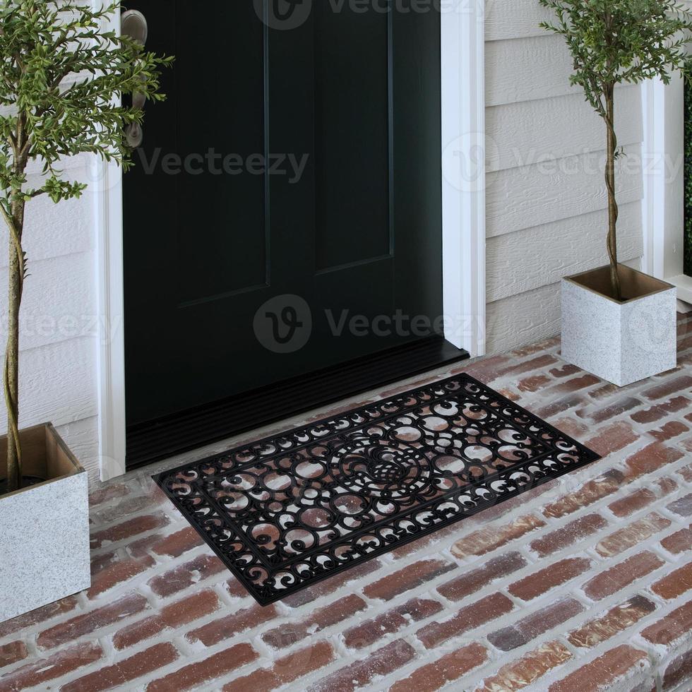 Designer Welcome Entry Doormat Placed on Solid Brick Floor Outside Entry Door with Plants photo