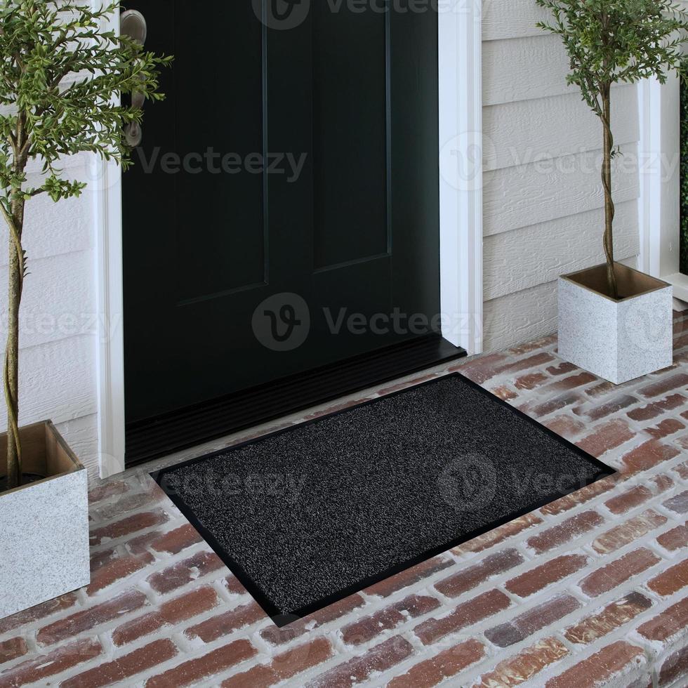 Designer Welcome Entry Doormat Placed on Solid Brick Floor Outside Entry Door with Plants photo