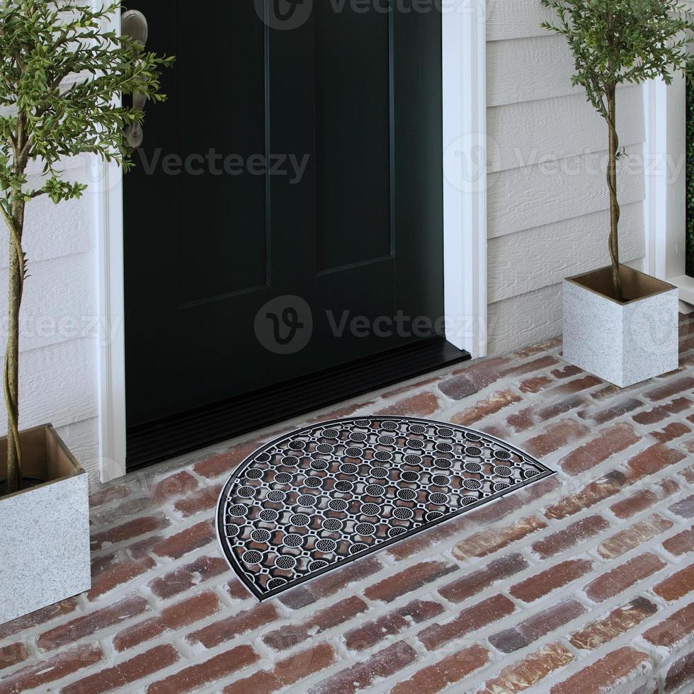 Designer Welcome Entry Doormat Placed on Solid Brick Floor Outside Entry Door with Plants photo