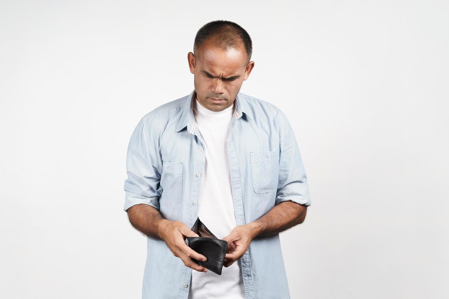 Upset mature man holding and looking inside his empty wallet on white background. financial crisis, bankruptcy, no money, bad economy Concept. photo