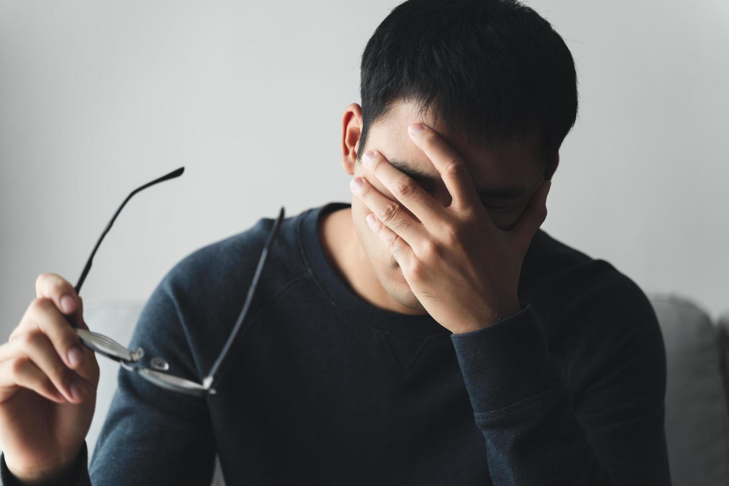 stressed man take off glasses massage eyes feel fatigue suffering from headache, exhausted man having eyestrain or astigmatism with overwork. photo