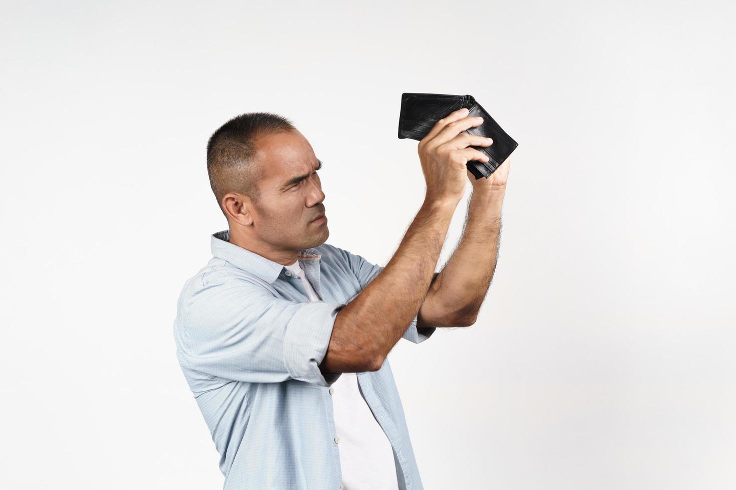 Upset mature man holding and looking inside his empty wallet on white background. financial crisis, bankruptcy, no money, bad economy Concept. photo