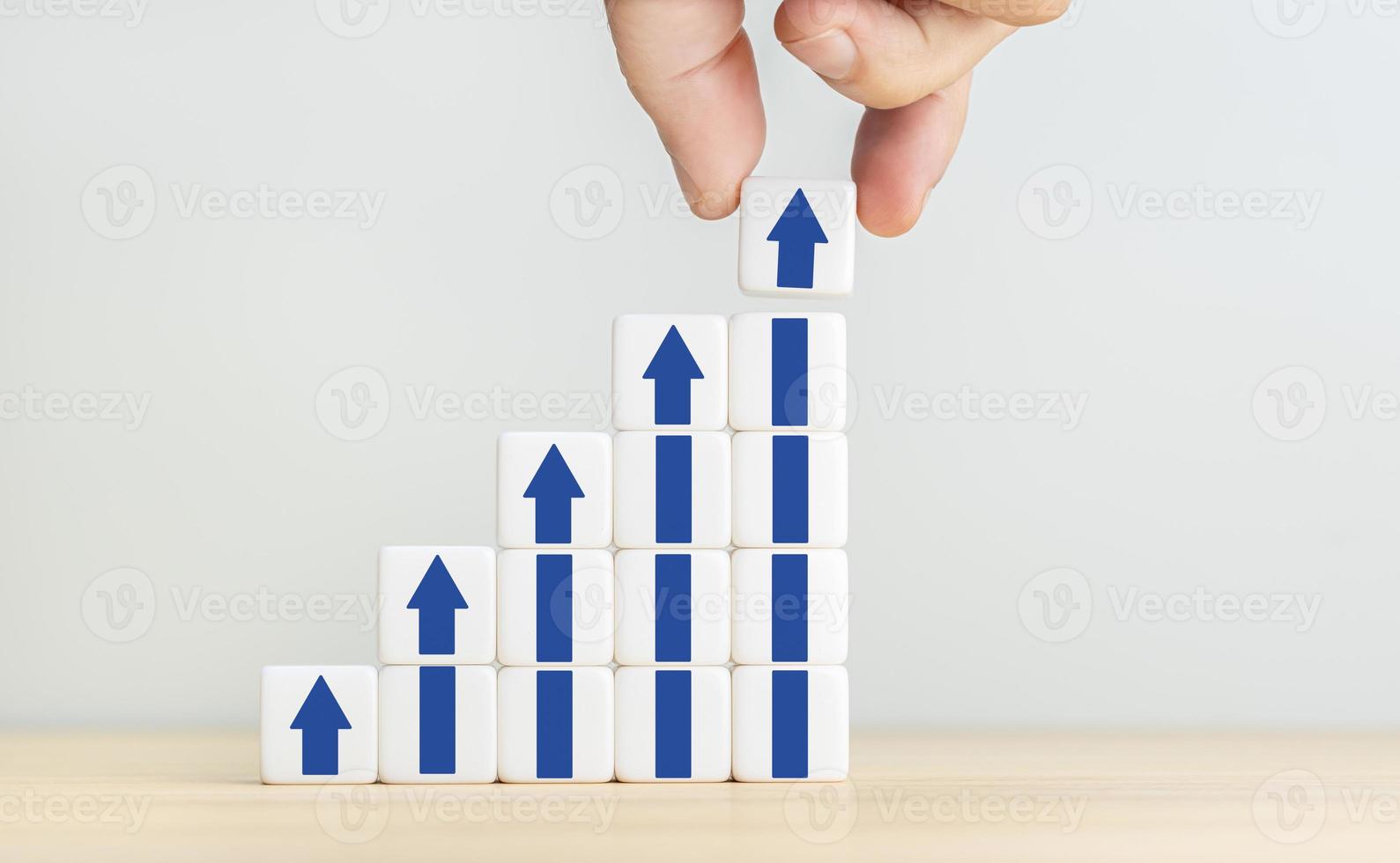 Growth, increase of business and economy concept. Human hand placing a cube with up arrow on top of other stacked blocks. Copy space photo