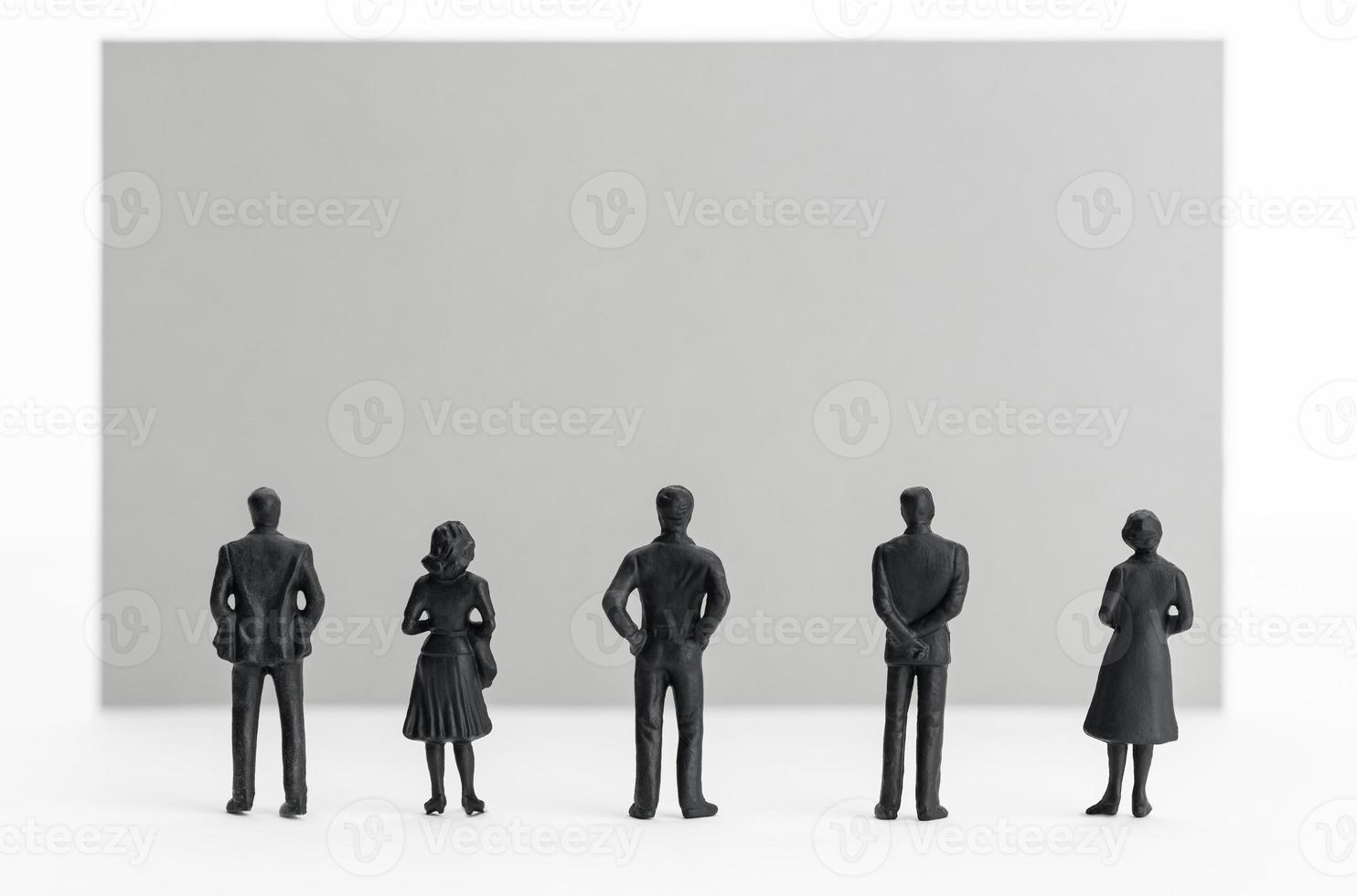 Group of people figurines looking at a blank sign. Template. Copy space photo