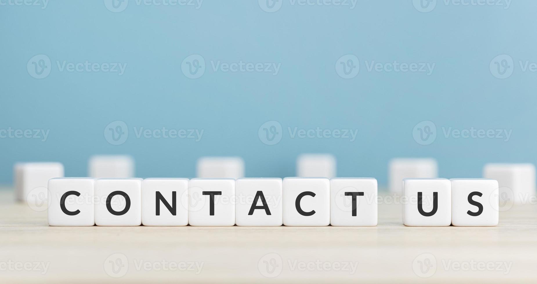 Contact us message on cube blocks on wood table. Copy space. Blue background photo
