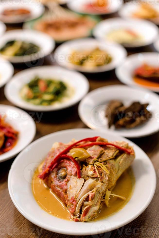 Fried fish in spicy curry sauce on white dish. indonesia food photo