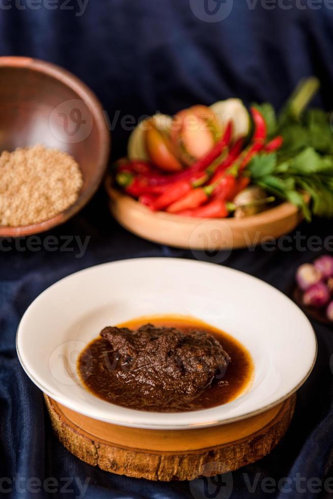 Rendang Padang. Spicy beef stew from Padang, Indonesia. The dish is arranged among the spices and herbs used in the recipe. photo