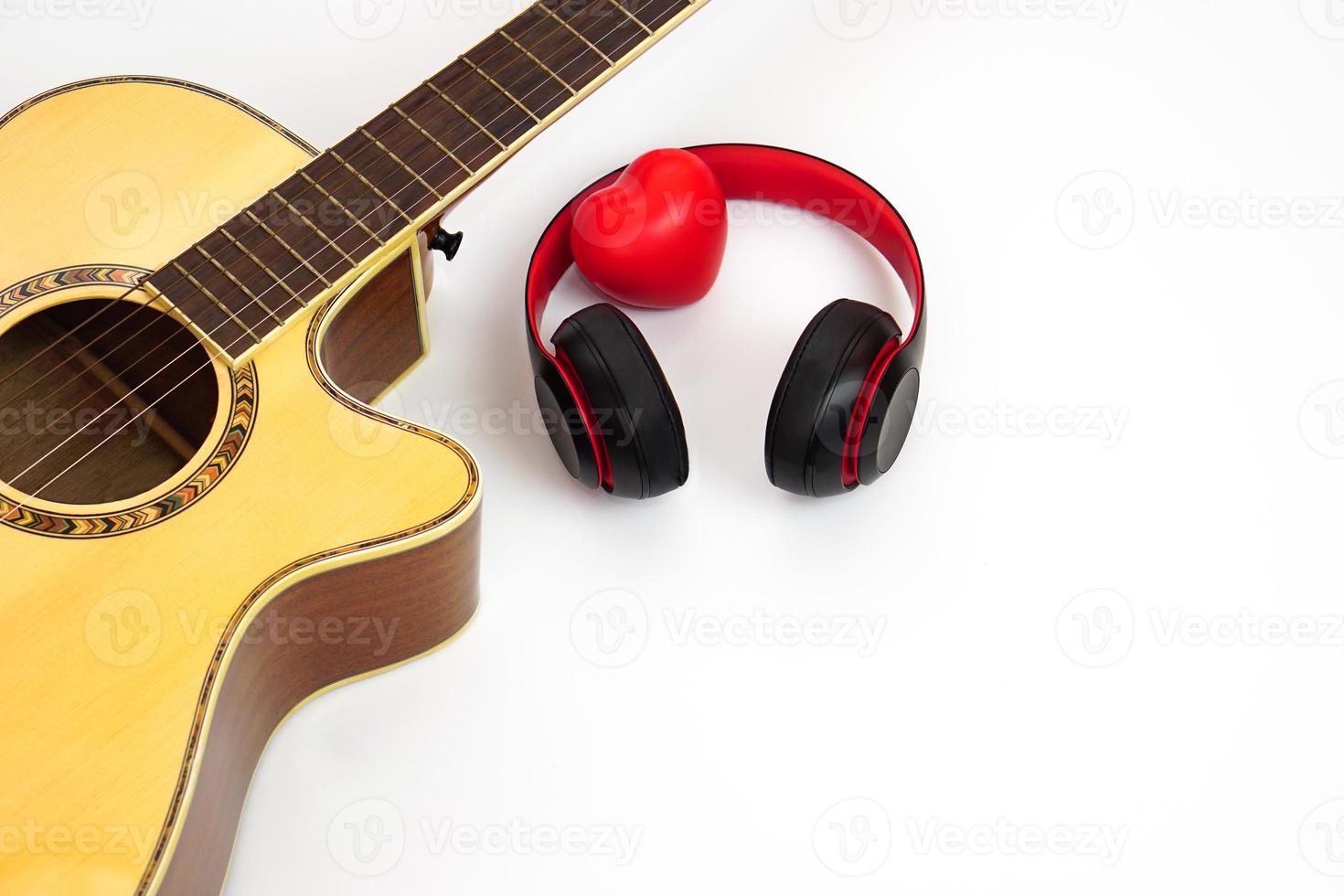 Acoustic guitar, headphones and red heart on a white background. Love and music concept. photo