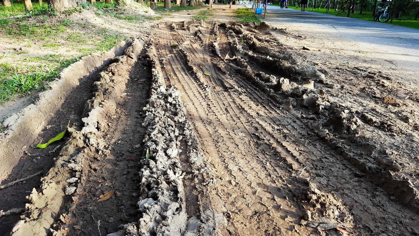 Cartire tracks on dark brown dirt road caused by rain water photo