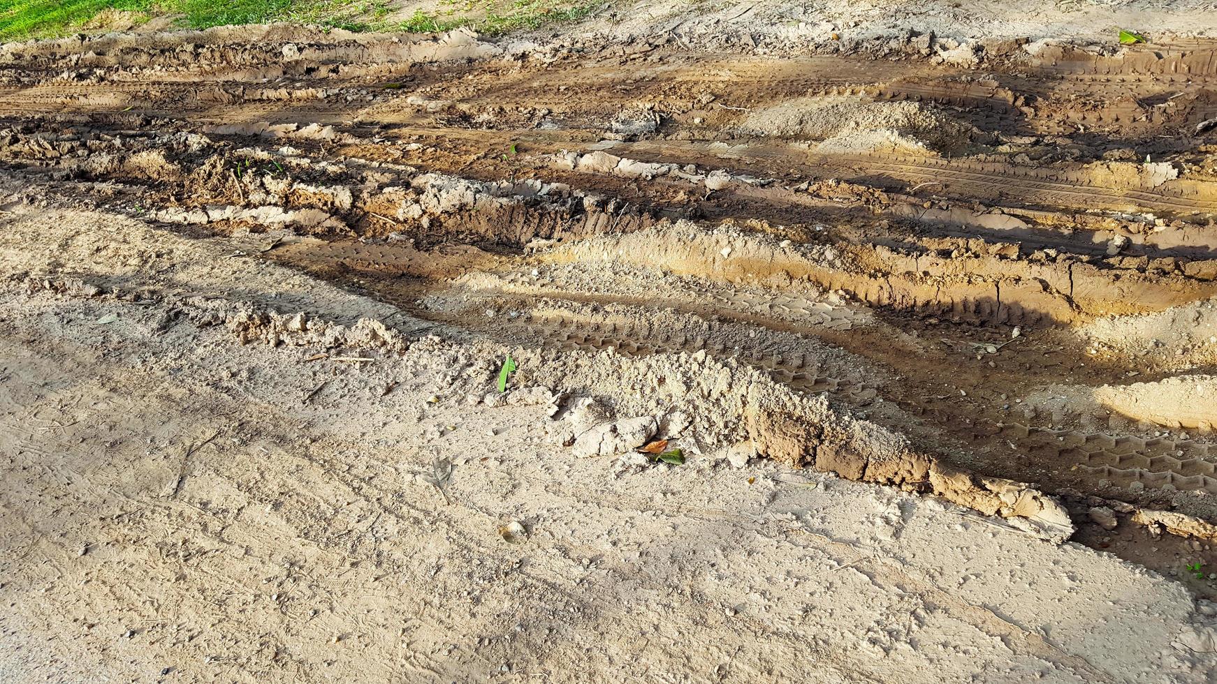 Cartire tracks on dark brown dirt road caused by rain water photo