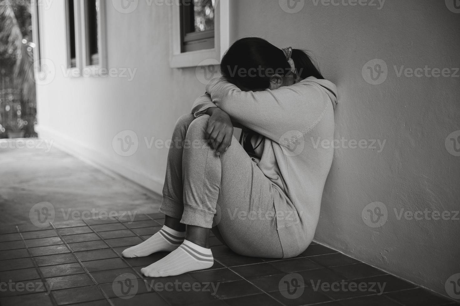 Schizophrenia with lonely and sad in mental health depression concept. Depressed woman sitting against floor at home with dark room feeling miserable. Women are depressed, fearful and unhappy. photo