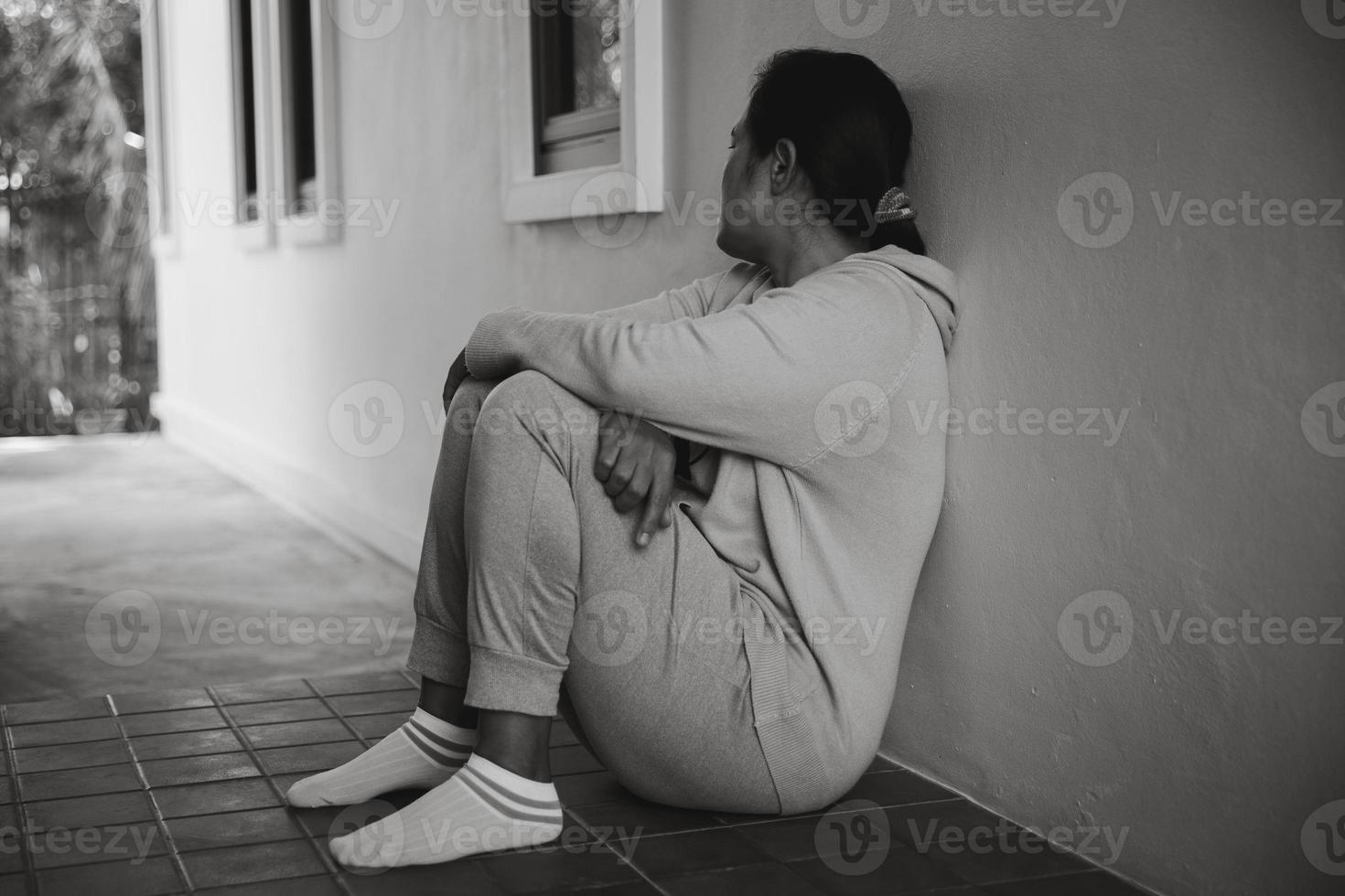 Schizophrenia with lonely and sad in mental health depression concept. Depressed woman sitting against floor at home with dark room feeling miserable. Women are depressed, fearful and unhappy. photo