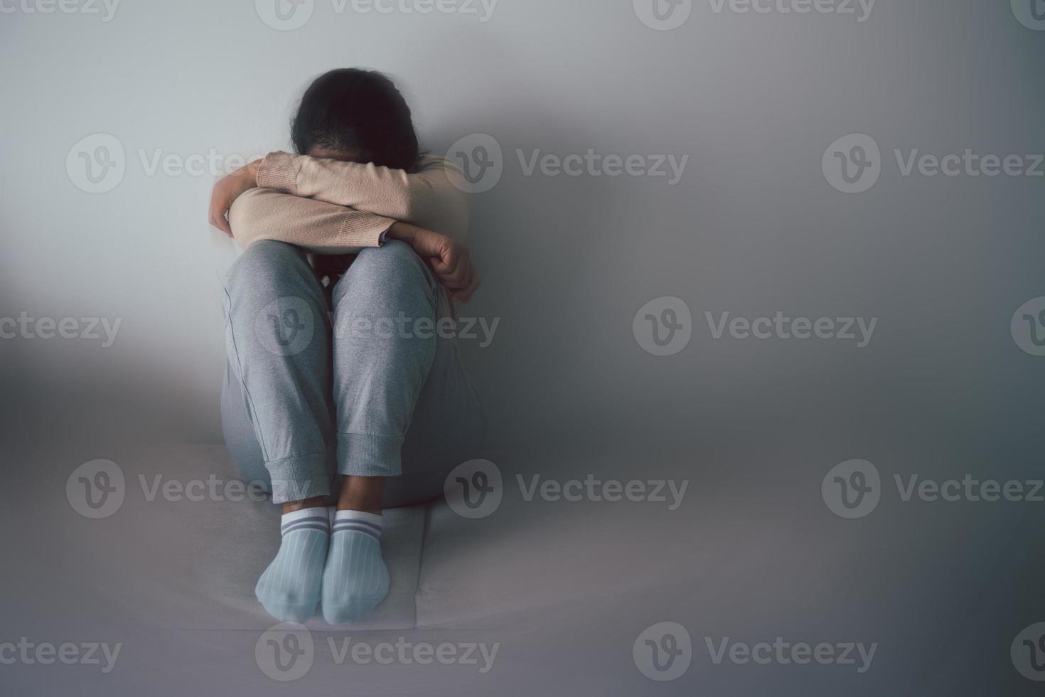 Schizophrenia with lonely and sad in mental health depression concept. Depressed woman sitting against floor at home with dark room feeling miserable. Women are depressed, fearful and unhappy. photo
