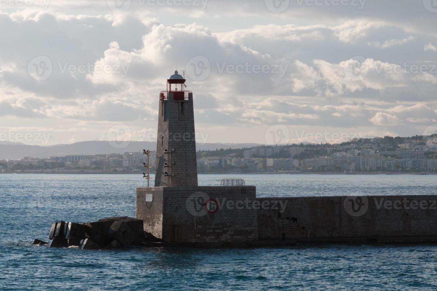 Lighthouse in the port, seascape. Beacon, sea, and clouds at sunset, Nice, France. photo