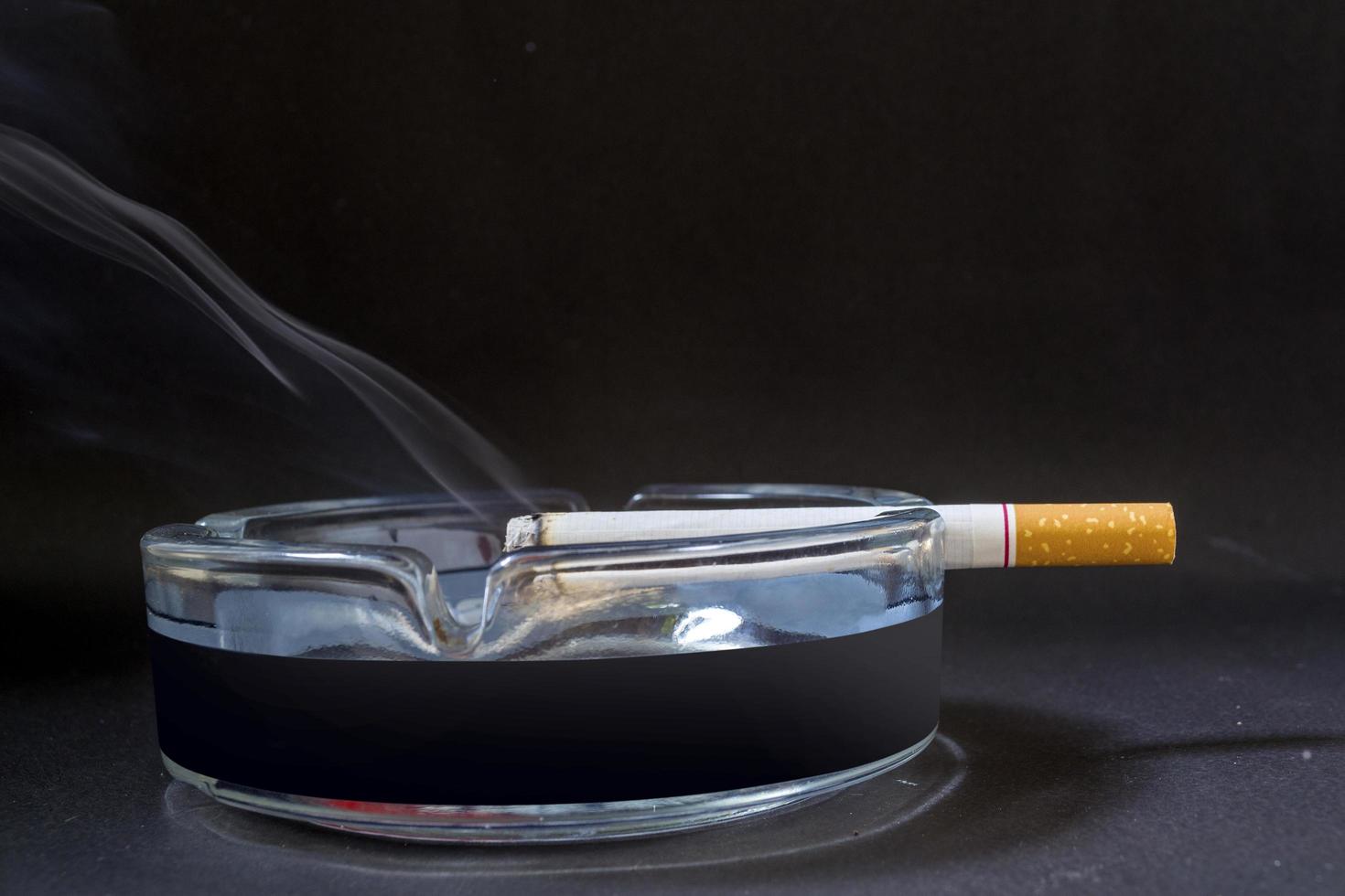 a cigarette with smoke shown against a black background photo