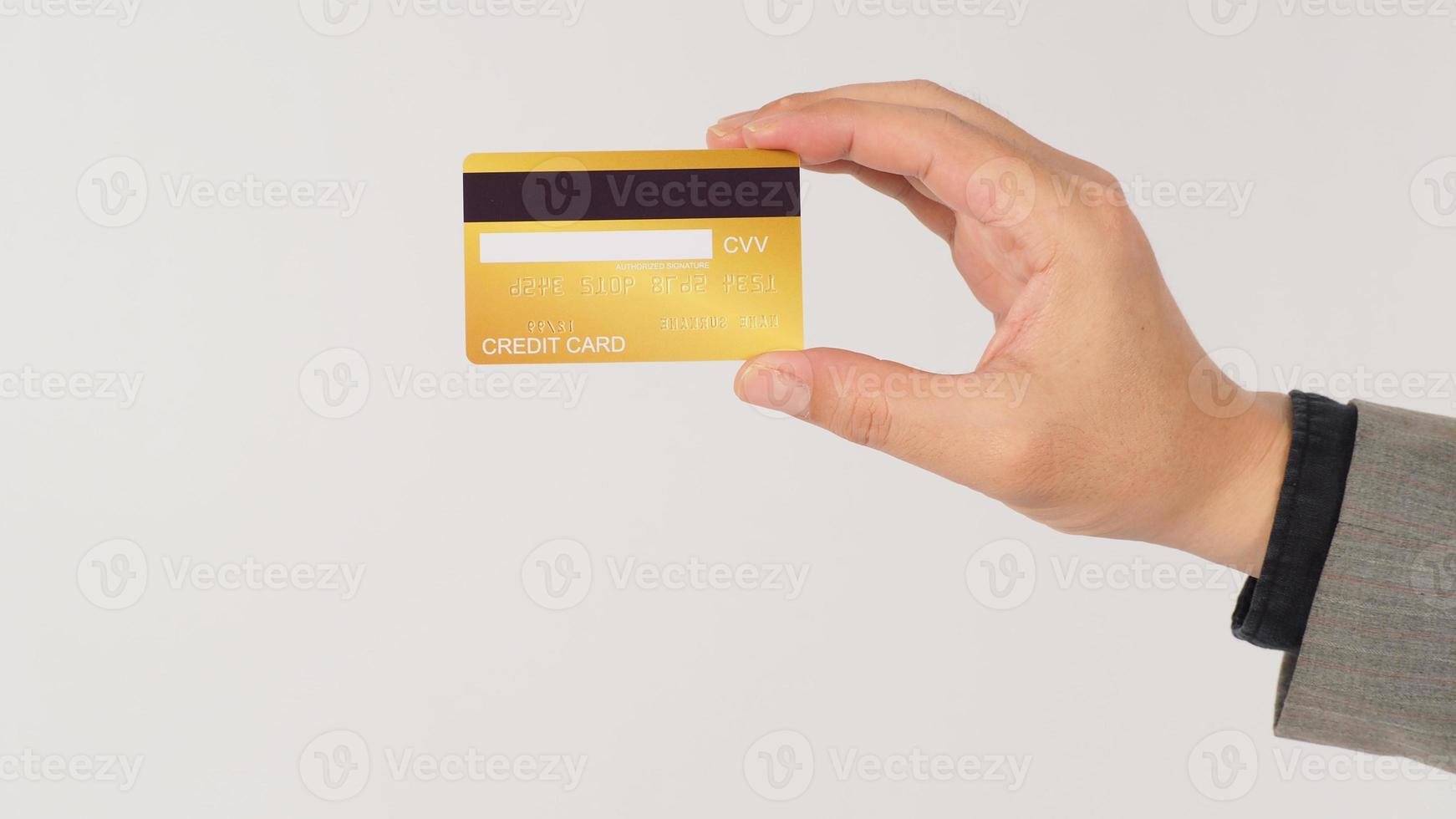 una mano retiene las tarjetas de crédito doradas y lleva un traje de fondo blanco. foto