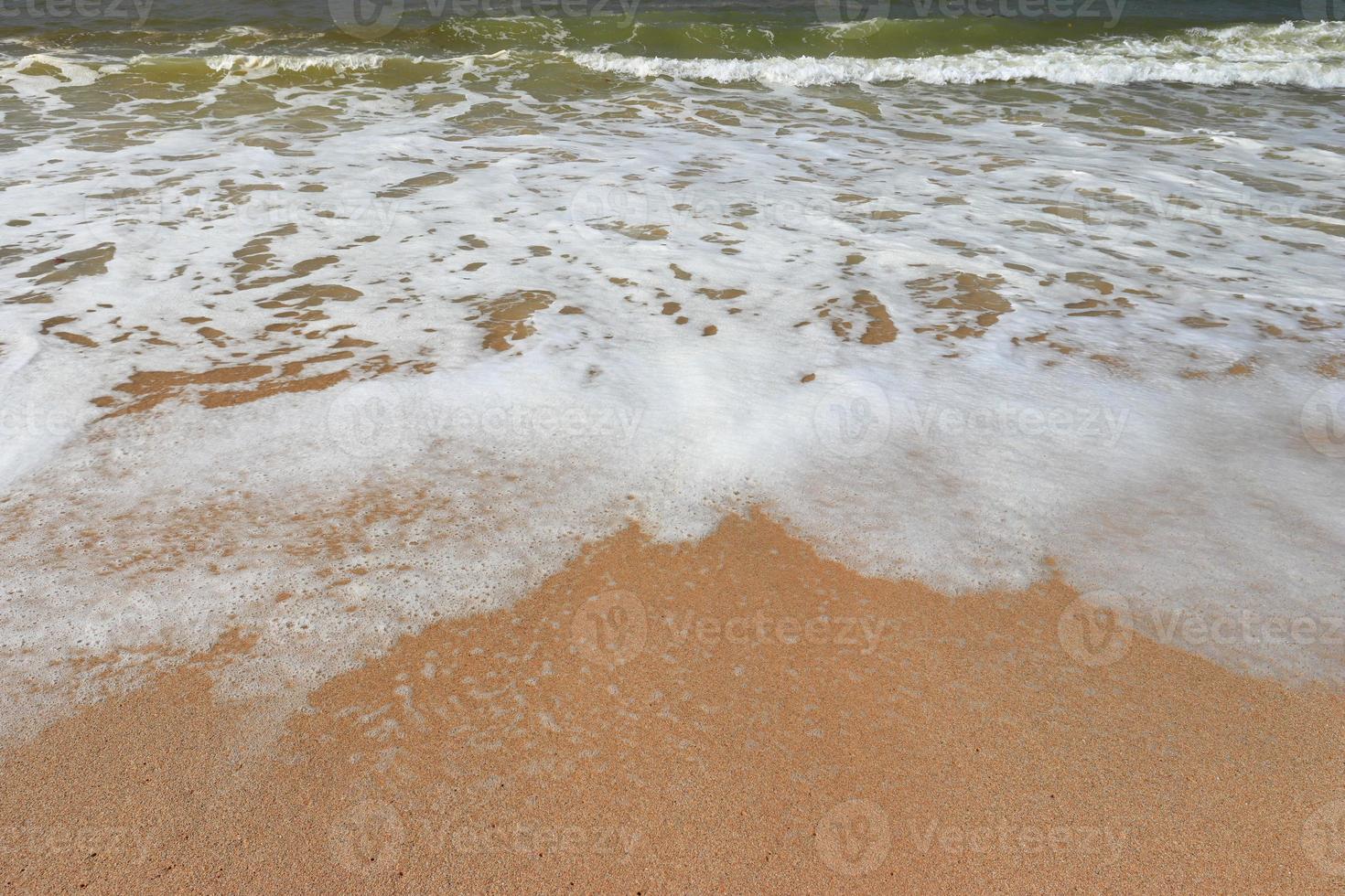 Water foam with smooth sand. Waves on shore of tropical beautiful sand beach on a sunny day photo