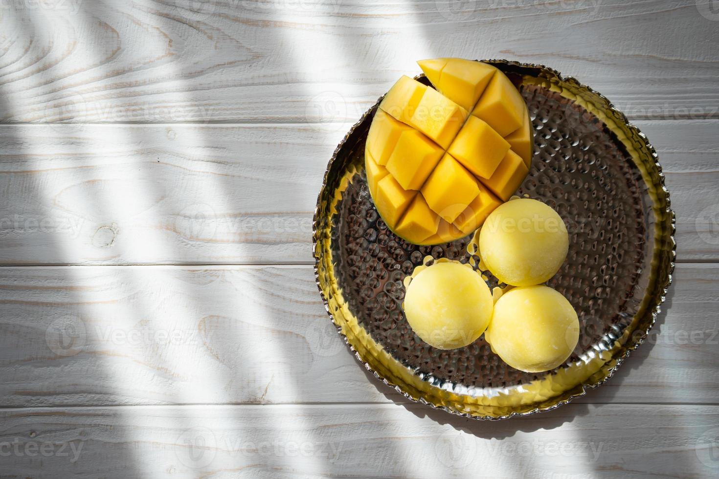 sabroso postre mochi con fruta de mango sobre fondo de madera foto