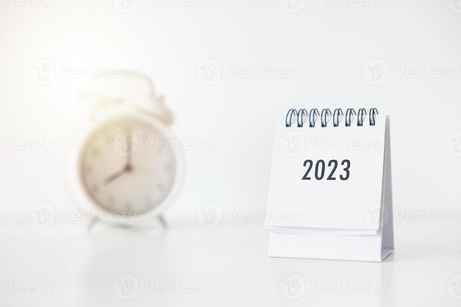 2023 business calendar and alarm clock on office table in new year day. Make a work plan for the start of the year. Concept about Celebration, Business, Christmas, New Year. photo