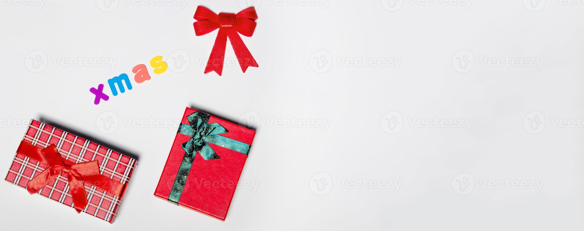 Red gift box with a green ribbon and a red bow, with the inscription Xmas on a white background. New year christmas concept. Flat lay festive mockup with copy space photo