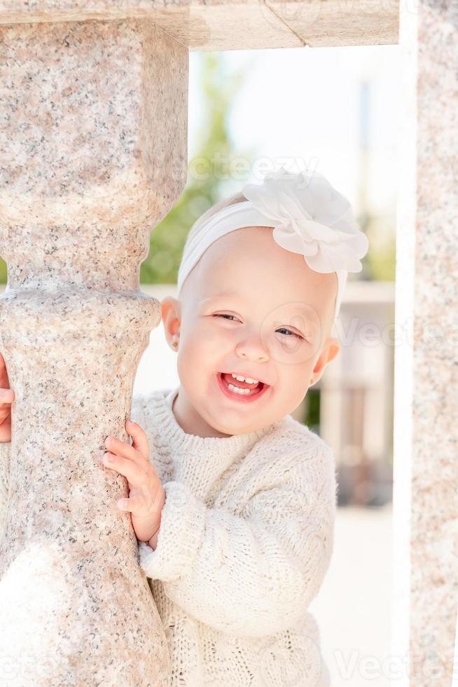 retrato de una niña rubia sonriente con el pelo corto, con una diadema de flores. niña linda y sonriente en la calle. foto