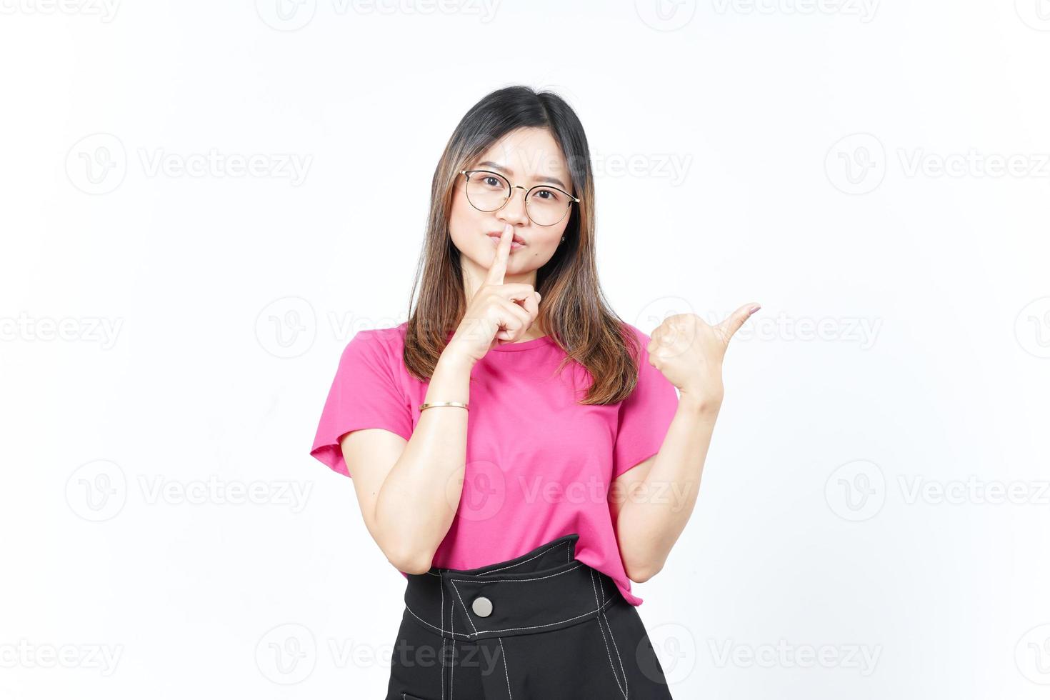 gesto shh, presentando y señalando el producto lateral usando el pulgar de una hermosa mujer asiática foto