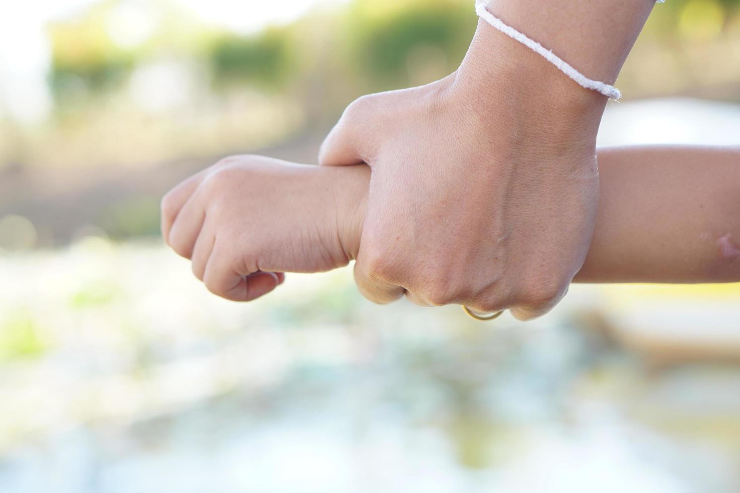 mano de la madre sosteniendo el brazo del bebé por miedo a caer al agua foto