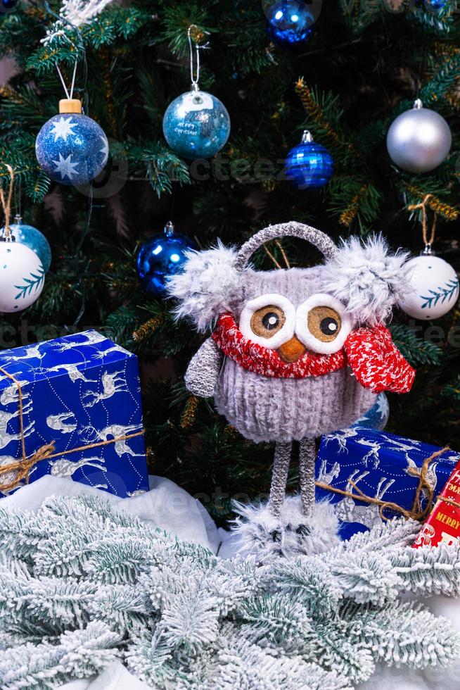 Soft plush toy owl with headphones and knitted scarf. Winter children's gift . Funny knitted red and white toy owl in a red hat and with big eyes photo