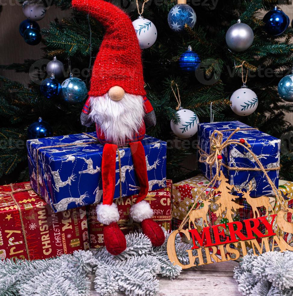 The inscription winter from a tree on a New Year's. On the spruce branches against the background of a snow cover are New Year's blue, white balls with spruce cones and a box with a gift. Christmas photo