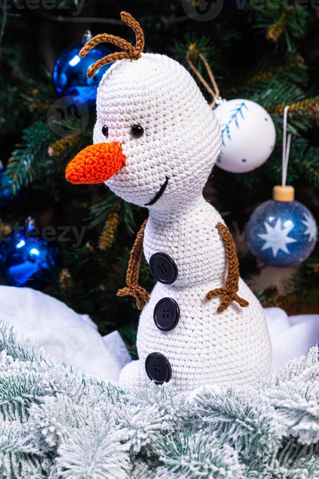 Knitted snowmen in colorful hats and scarves on a blue background. The concept of Christmas, New Year and winter fairy tale. photo