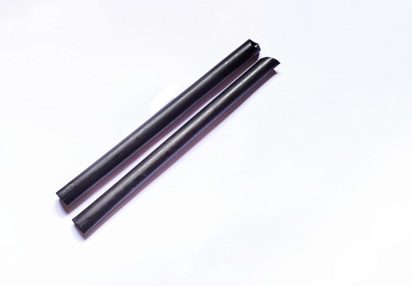 isolated black plastic straw on white background photo