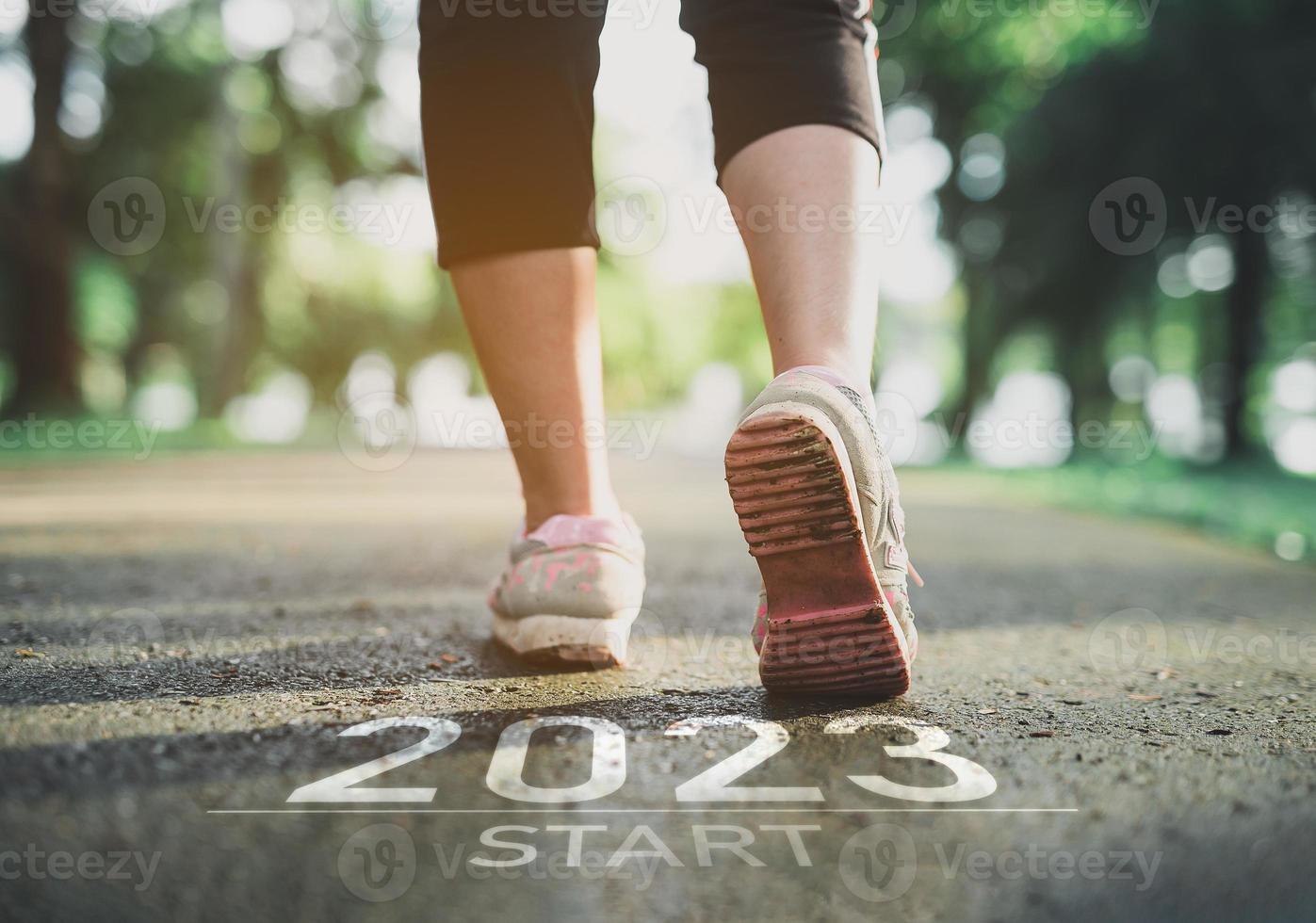 Sport woman runner foot shoe start into the new year 2023. Start up of runner woman running on nature race track go to Goal of Success. People running as part of Number 2023. Sport health care. photo