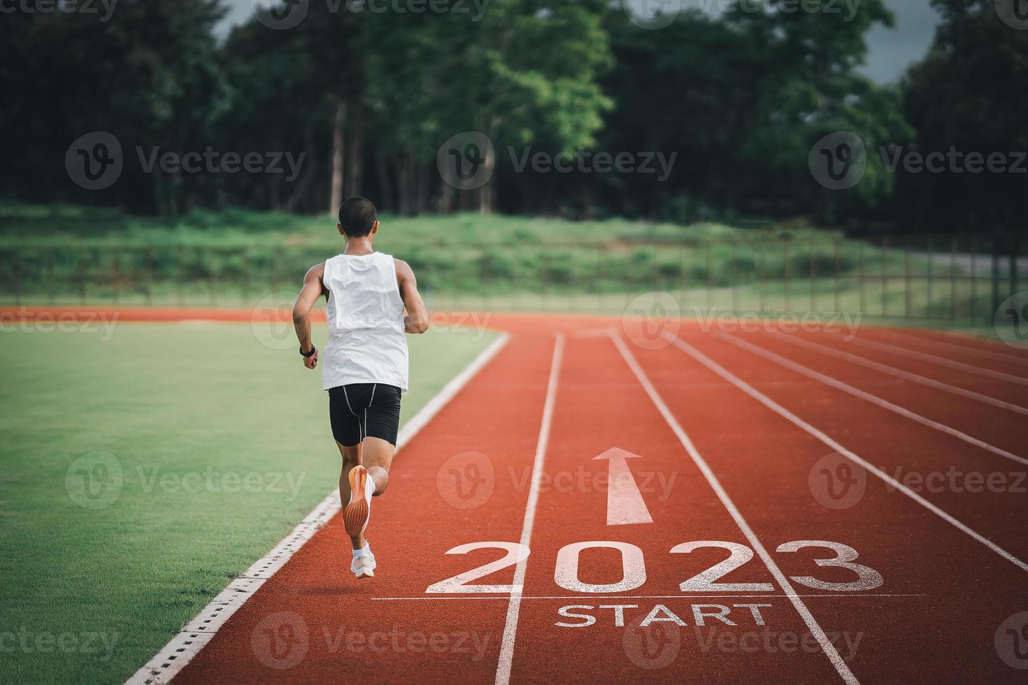 Happy new year 2023 Sport man runner running into the new year 2023. Start up of runner man jogging at stadium go to Goal of Success. People running as part of Number 2023. Sport health care. photo