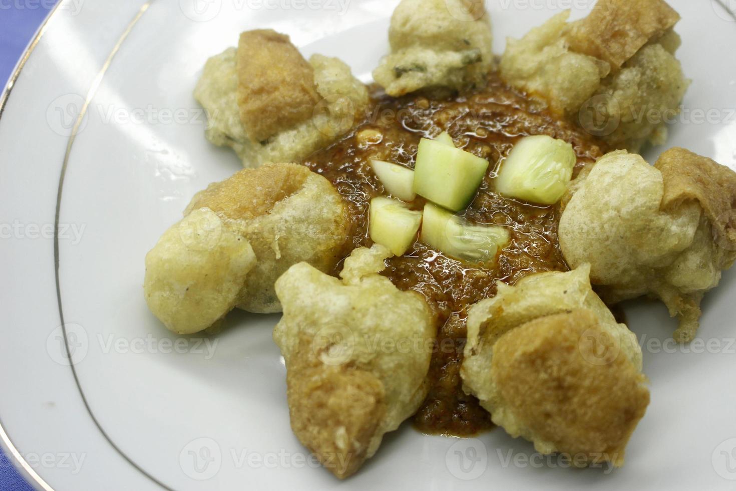 Batagor with peanut sauce and cucumber close up photo