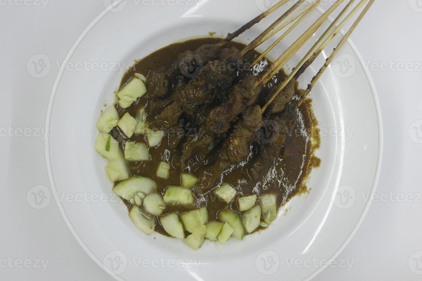 Sate or satay with peanut sauce and cucumber from top photo