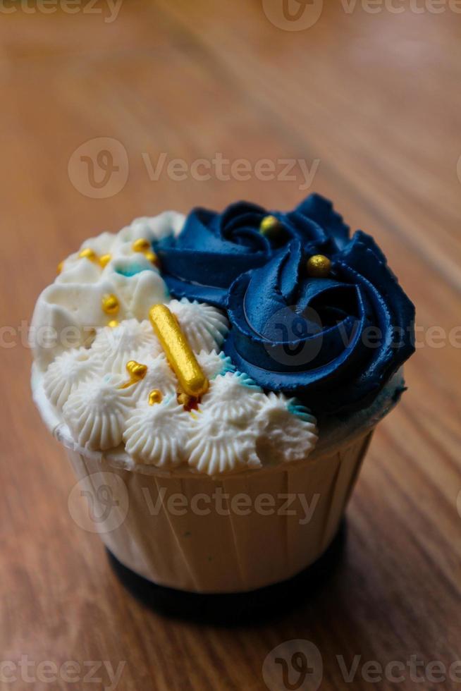 Luxurious and elegant cupcakes, with white cream and navy blue with gold sprinkles. photo