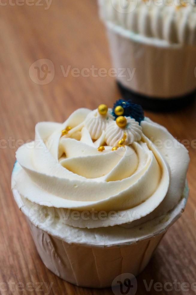 Luxurious and elegant cupcakes, with white cream and navy blue with gold sprinkles. photo