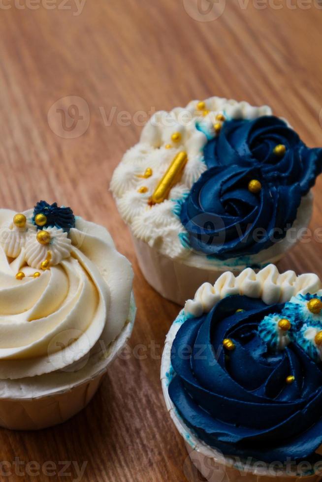 Luxurious and elegant cupcakes, with white cream and navy blue with gold sprinkles. photo