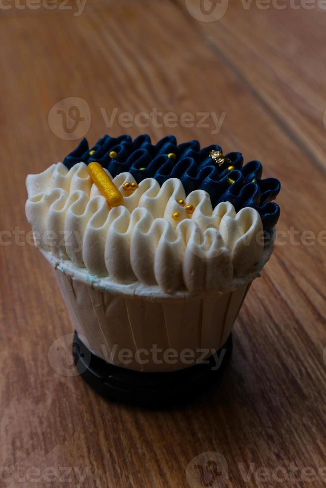 Luxurious and elegant cupcakes, with white cream and navy blue with gold sprinkles. photo