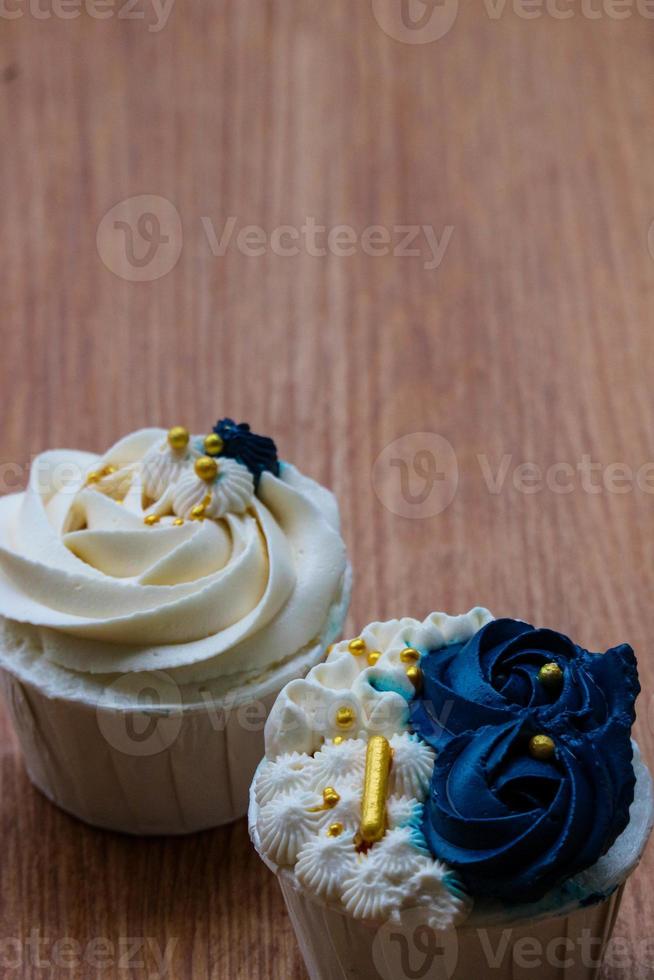 Luxurious and elegant cupcakes, with white cream and navy blue with gold sprinkles. photo