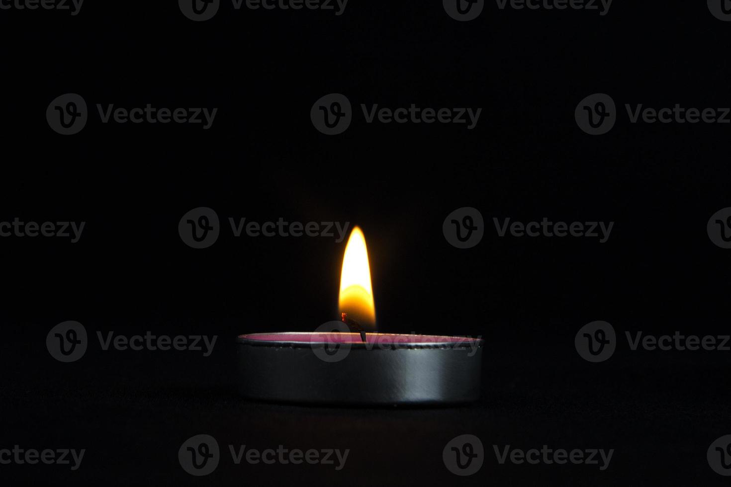 un primer plano de una vela encendida con llama amarilla, una luz de vela en la oscuridad, se quema y después de un rato una ráfaga de viento la apaga. foto