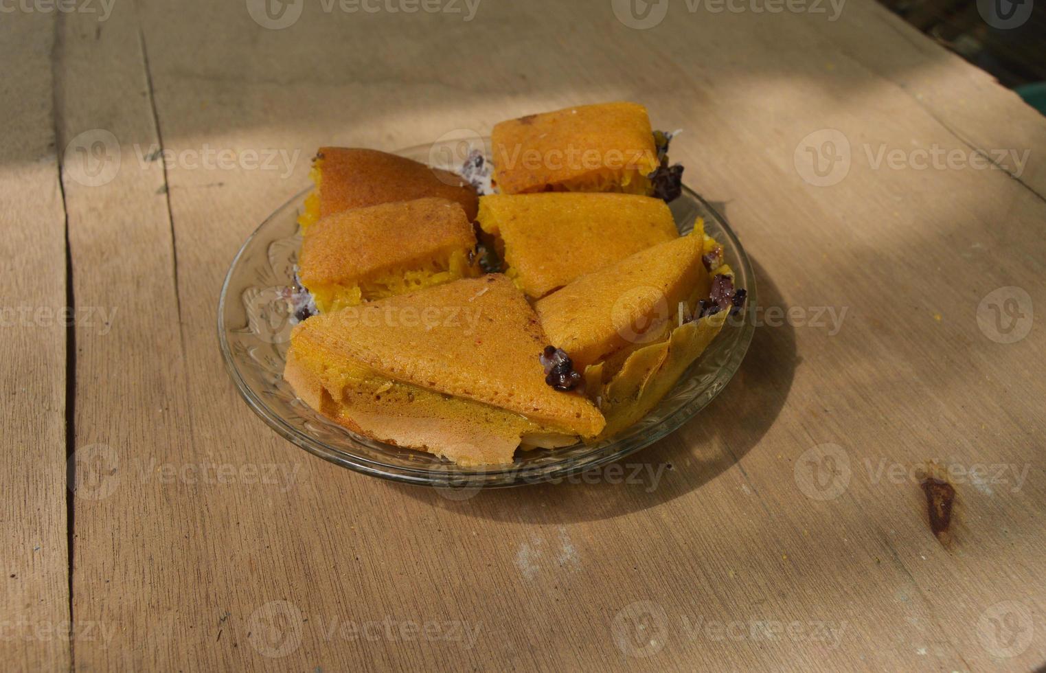 Terang Bulan food made from flour and stuffed with black sticky rice originating from Indonesia. with plates and wooden background. photo