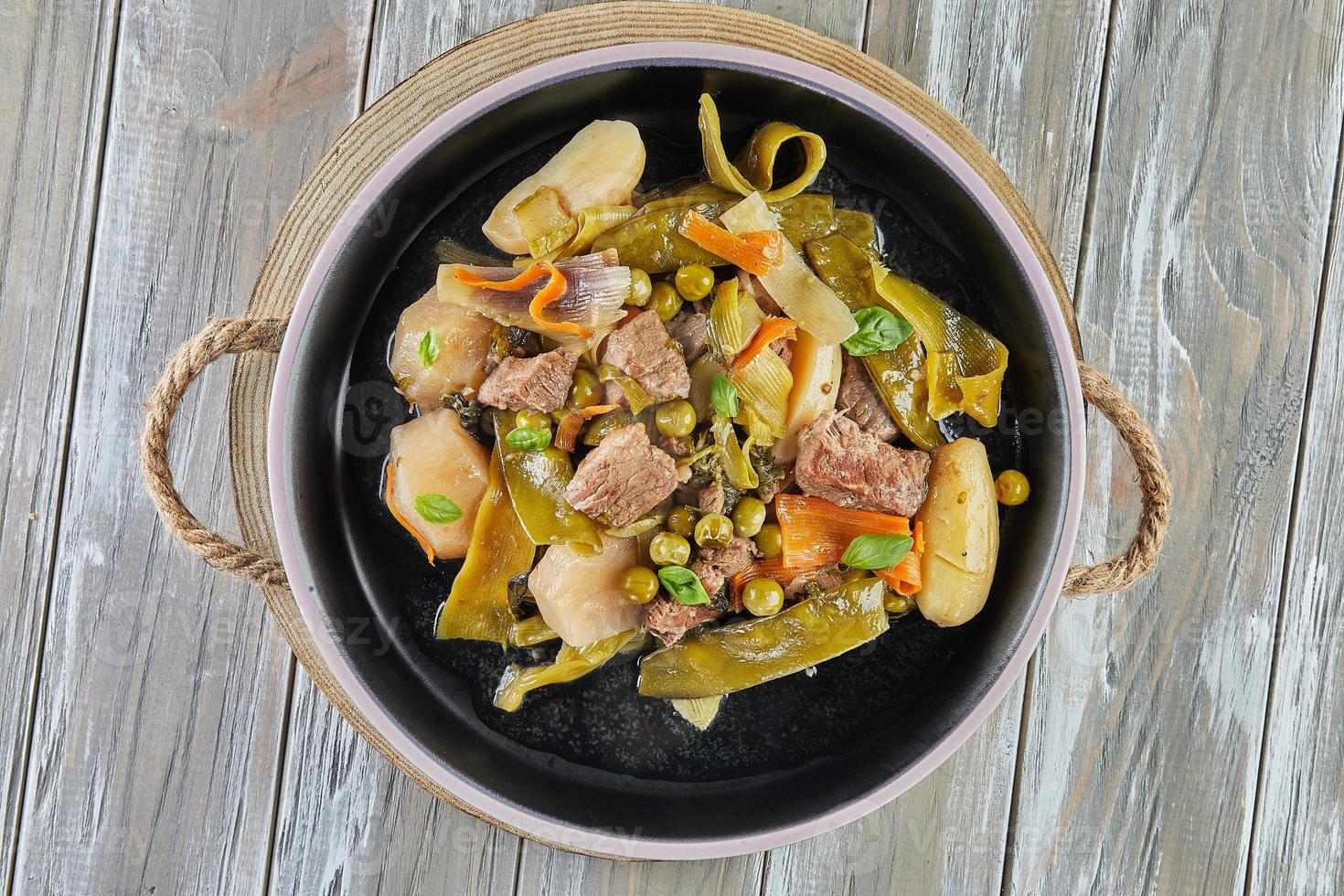 Lamb stew with seasonal vegetables on black plate photo