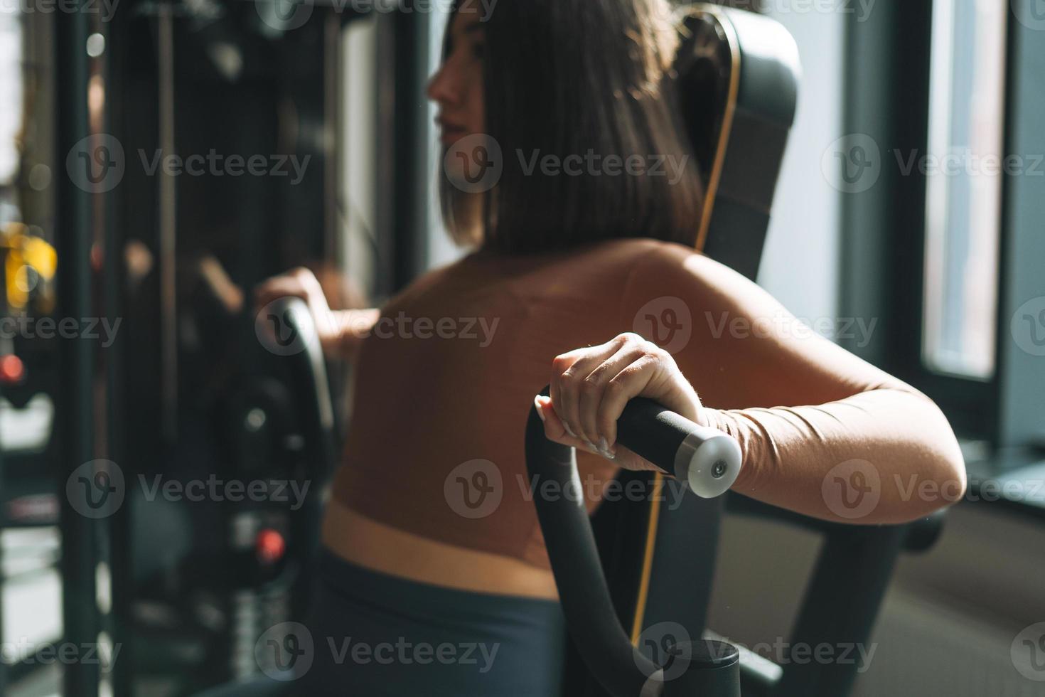 joven mujer morena fitness entrenando para equipos de músculos de la mano en el gimnasio, enfoque selectivo foto