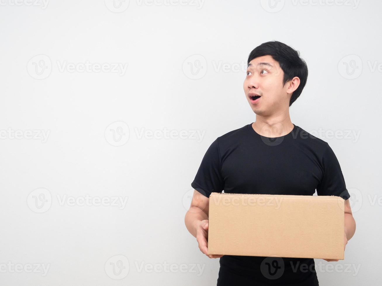 Young man holding parcel box and looking at copy space photo