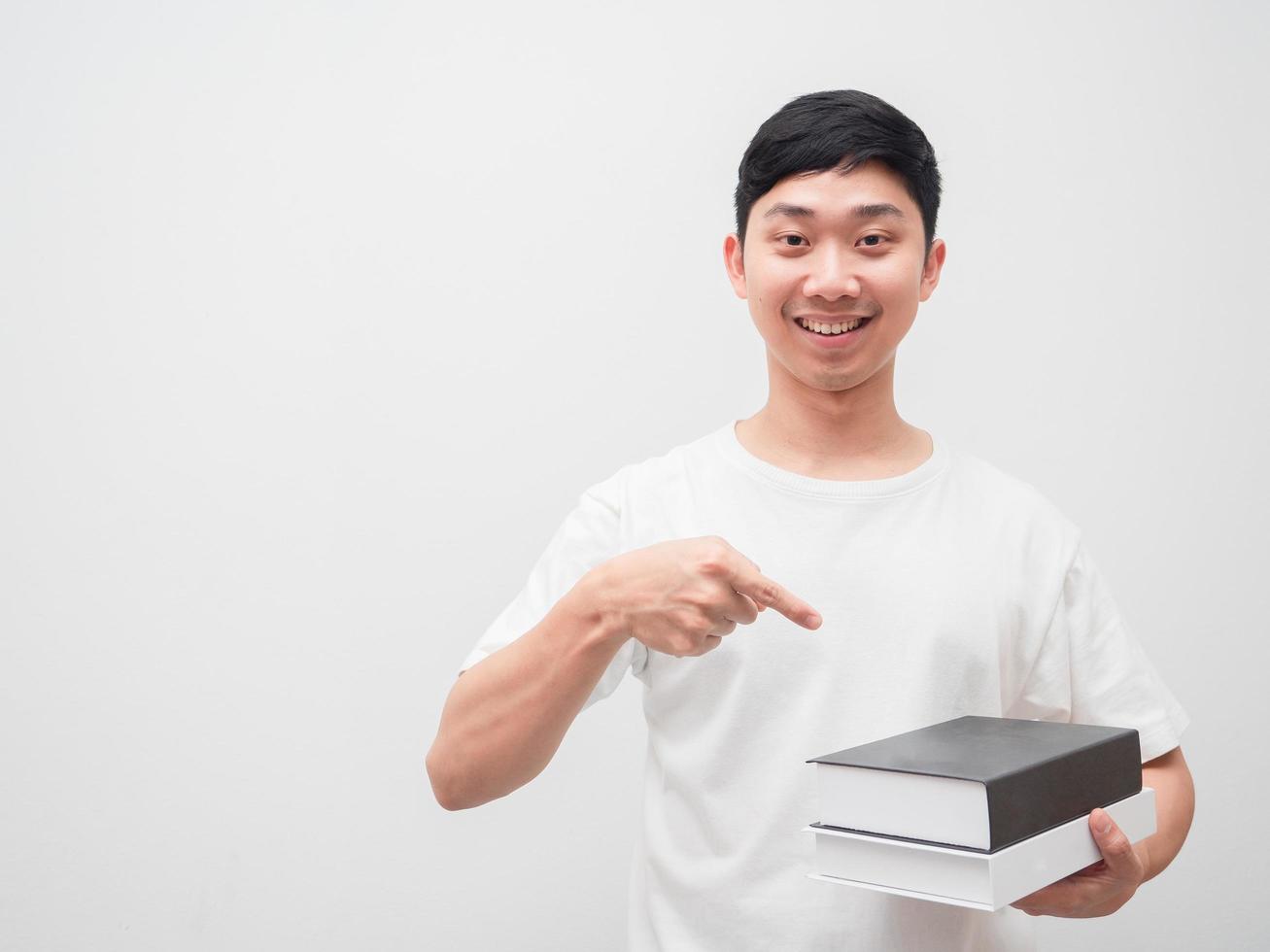 Asian man point finger at books in hand with happy smile look at camera on white isolated background photo